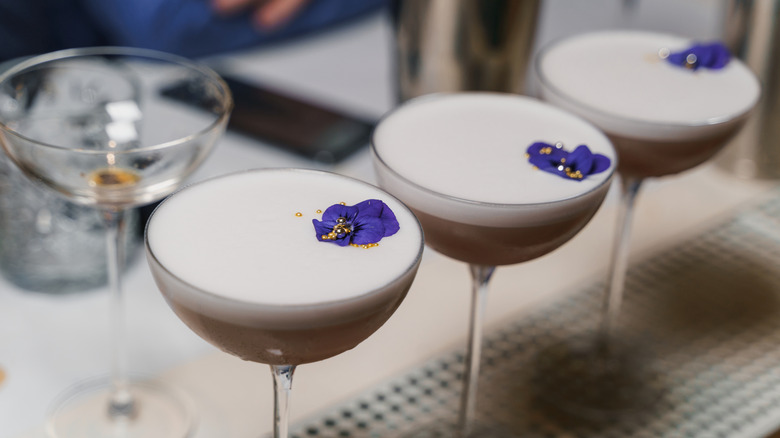 Three cocktails with flower and edible gold bead garnish