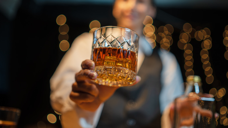 A professional presenting a stylish glass of whiskey to the camera