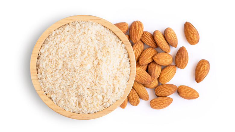 Almond flour in a bowl next to raw almonds