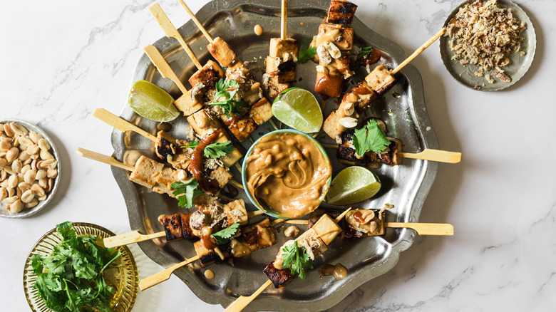 Satay tofu skewers with toppings on metal plate