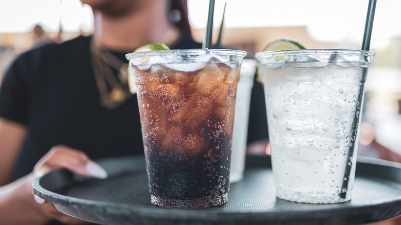 Server carrying a tray of sodas