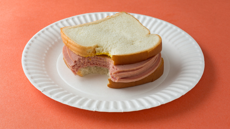 Bologna sandwich with mustard on paper plate