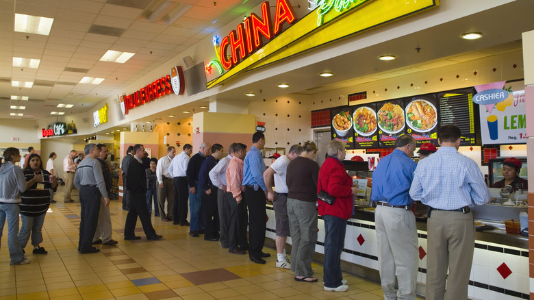 Diners line up to order food at mall food court restaurant