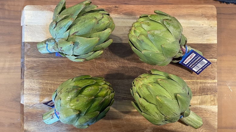 Whole artichokes on a cutting board