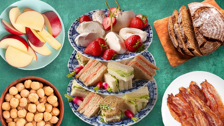 Assortment of tea sandwiches in the middle of the image, with separate ingredients like bread and apples on the side
