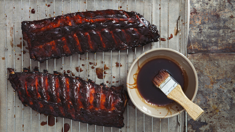 Ribs are marinated in barbecue sauce on a grate.