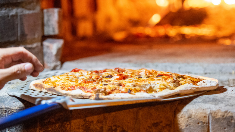 Pizza on peel in brick oven