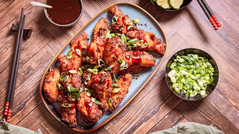 Korean dry-rubbed chicken wings on serving platter with dipping sauce and garnishes