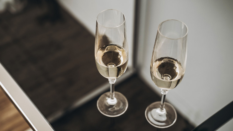 two champagne glasses on a glass table