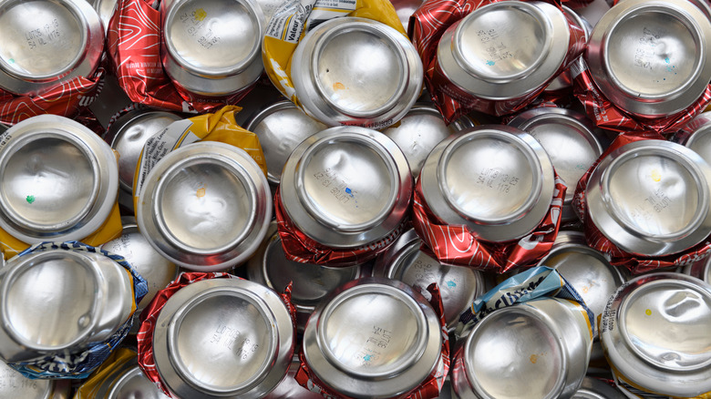 Rows of crushed beer cans seen from the bottom with different color ink dots
