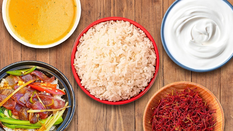 Rice and various ingredients in bowls on wooden table
