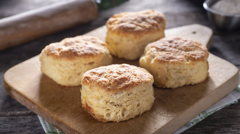Four biscuits are shown on a wooden cutting board.