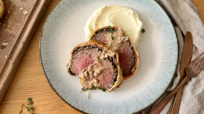 Sliced beef wellington with mashed potatoes on plate