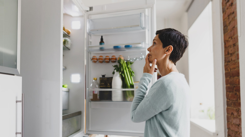 Woman looking inside open refrigerator