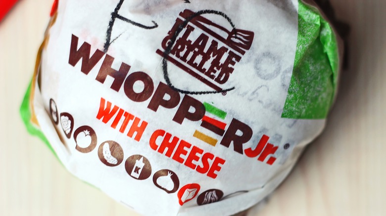 A Burger King Whopper Jr. in a paper wrapper on a table