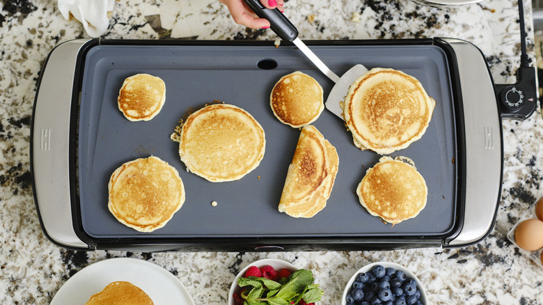 Person cooking pancakes on a griddle