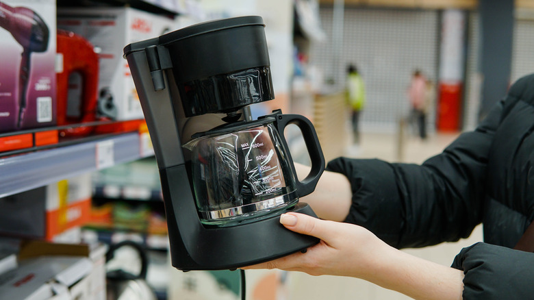 A person shopping for a coffee maker in a store