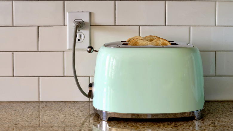 Blue toaster sitting on countertop with toasted bread in it