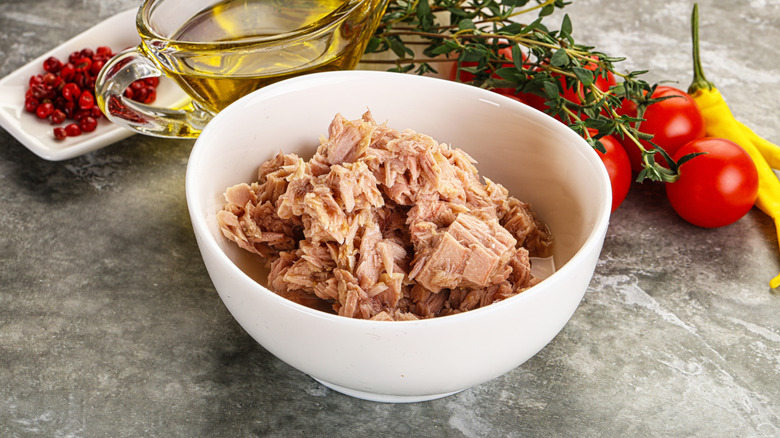 Bowl of canned tuna next to oil and veggies
