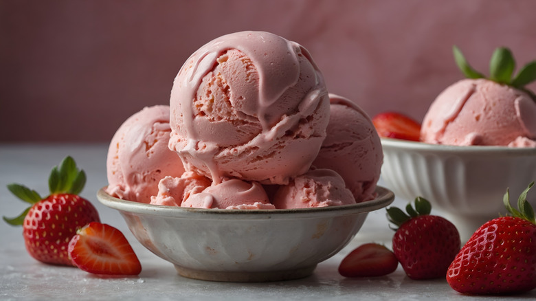 A bowl of strawberry ice cream with fresh strawberries