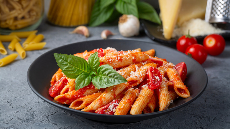 a bowl of pasta with spicy red sauce and basil