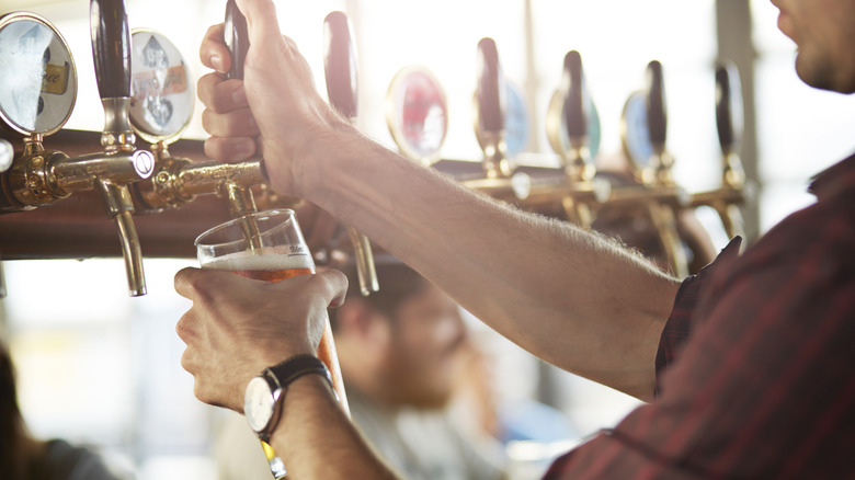 Person pouring a beer on tap