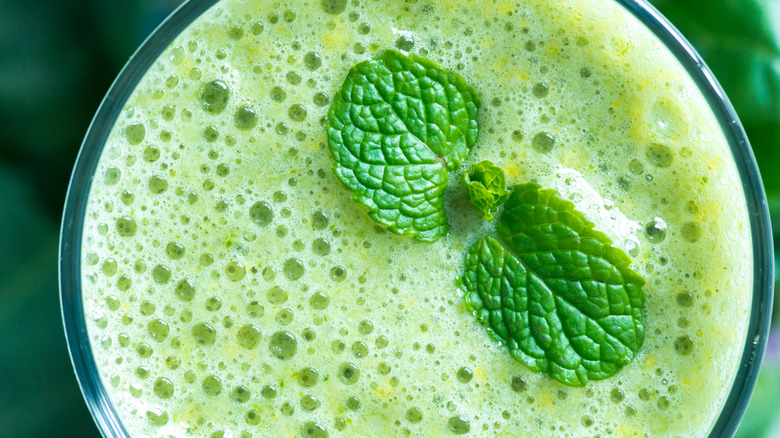 A frothy green drink garnished with mint