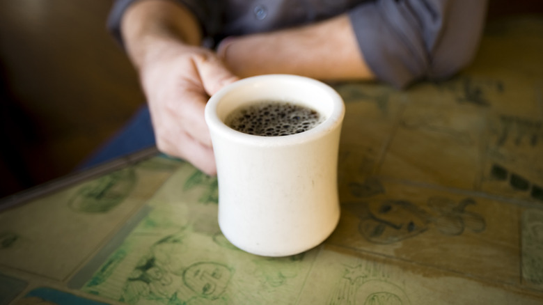 Man holding white mug of coffee