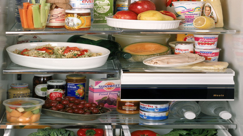 Food and drinks fully filling two refrigerator shelves