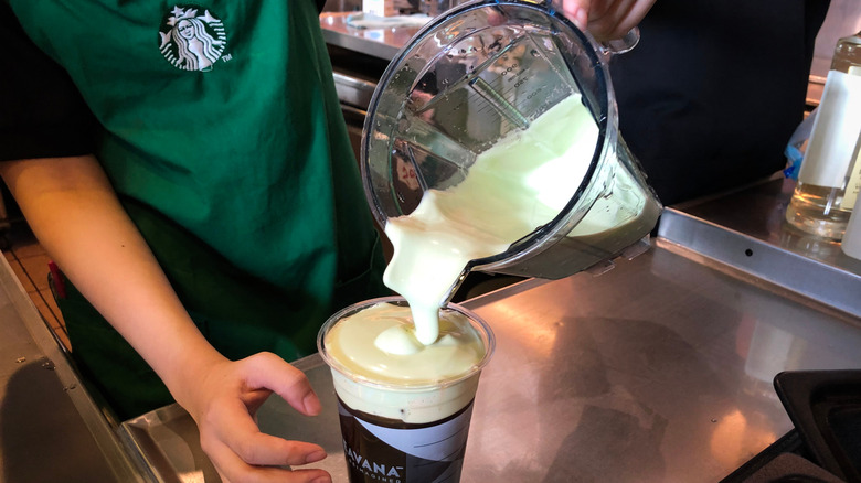 Starbucks barista adding matcha cold foam to tea