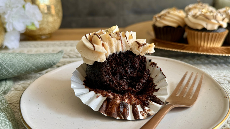 Half eaten chocolate stout cupcake with frosting on plate