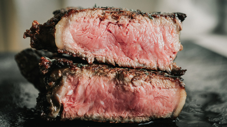 Two pieces of grilled steak with a layer of fat on the edge of each one