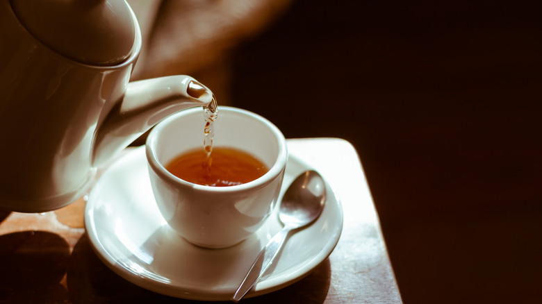 Tea being poured into a cup on a table.