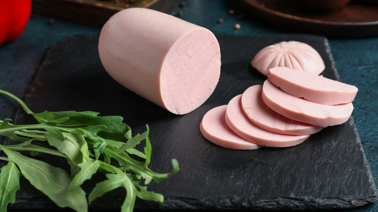 Bologna slices on cutting board with arugula