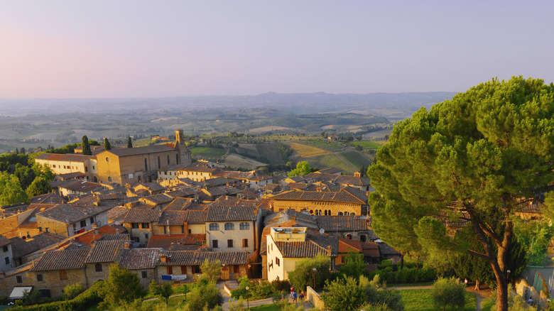 A photo of the landscape of Tuscany with a small village and hills in the distance