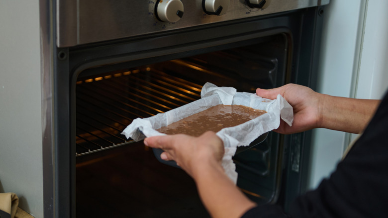 Person putting cake pan in oven