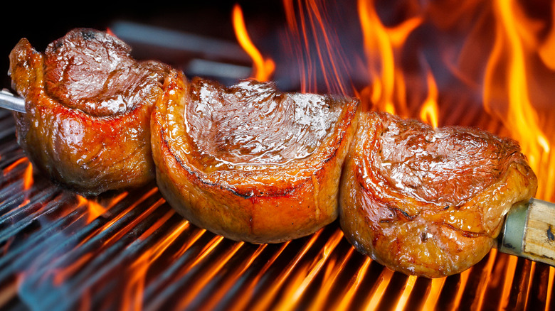 Picanha steaks on a metal skewer on top of a grill