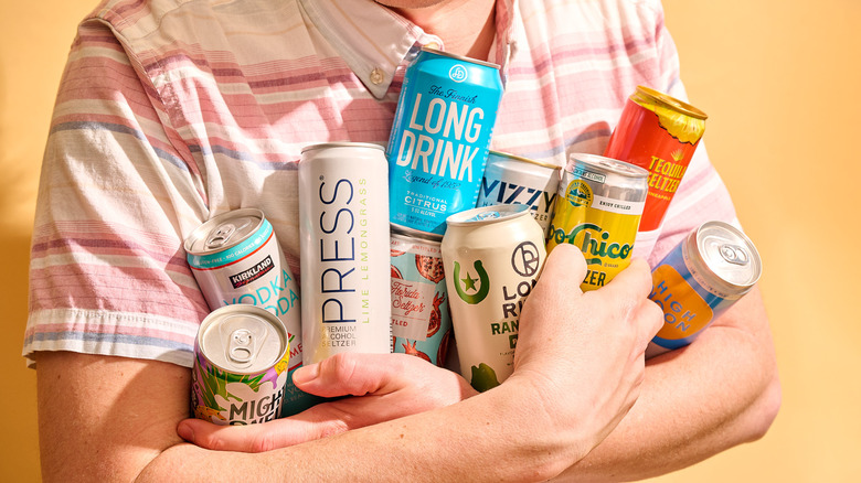 A man holding 10 cans of hard seltzers