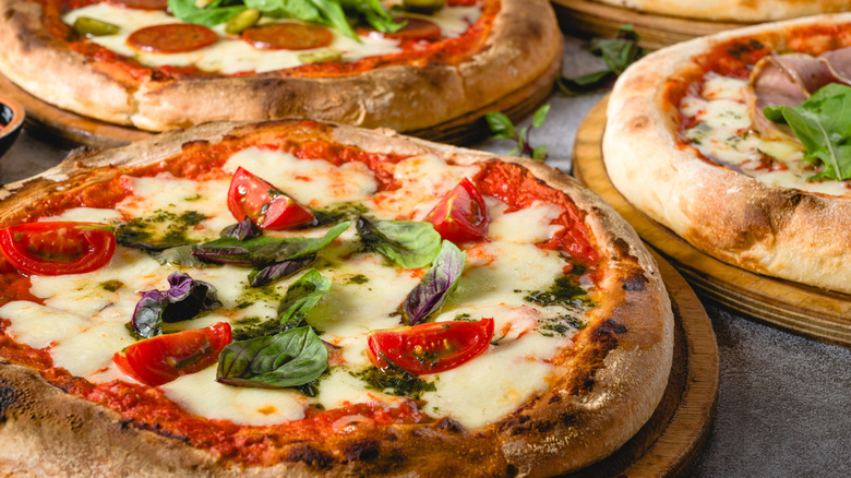Three neapolitan pizzas on round wooden boards