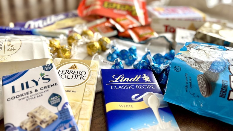 Arrangement of white chocolate bars and candies on wooden table