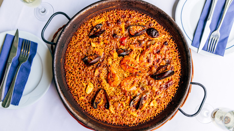 paella in a pan sitting on a dining table