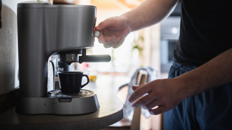 A person making coffee at home with an espresso machine