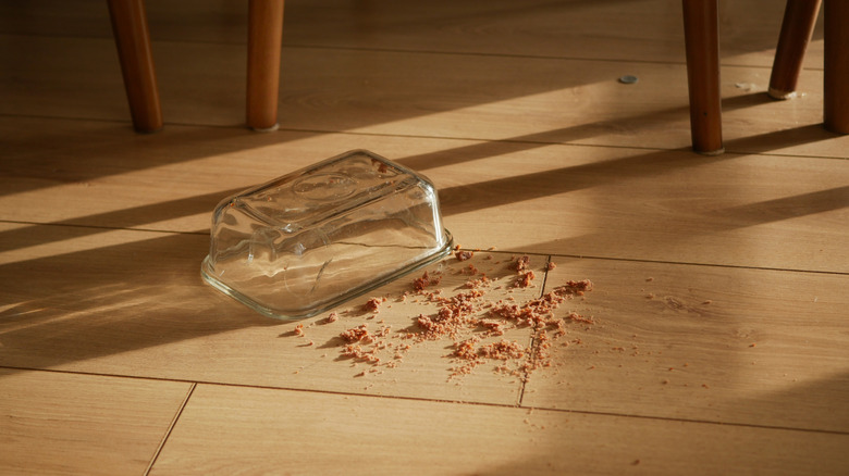 Glass dish in hardwood kitchen with crumby floor