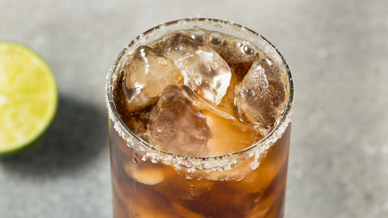a Batanga cocktail with a lime in the background