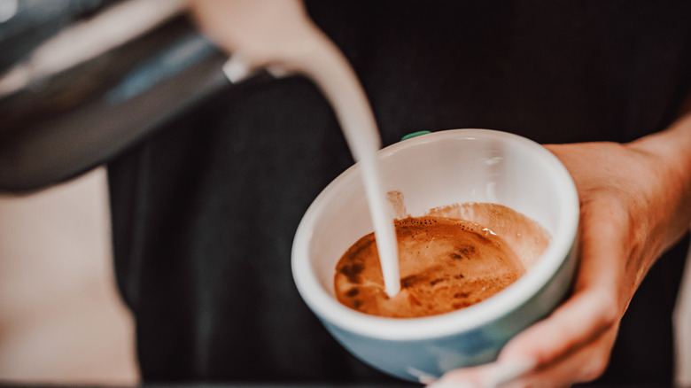 Pouring creamer into coffee mug