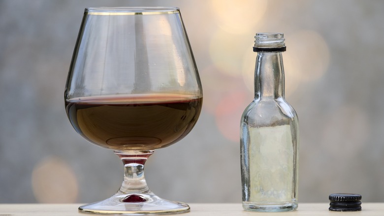 A snifter of bourbon placed alongside a small bottle of water