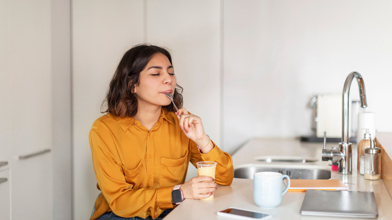 Woman sitting at kitchen table eating pudding