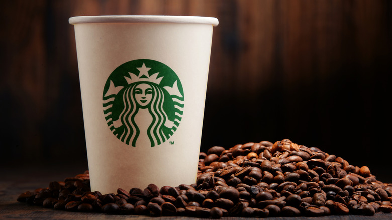 A Starbucks cup sits in a pile of coffee beans