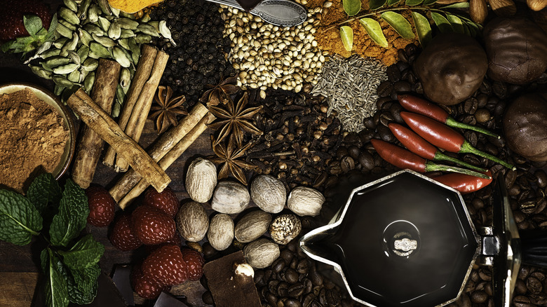 overhead shot of moka pot and spices, berries, chilies, and mint