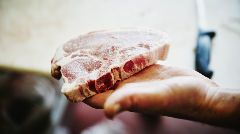 hand holding a raw pork chop